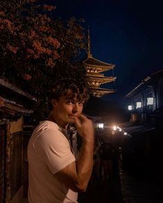 a man standing in front of a building at night with his hand on his face