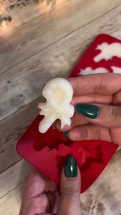 a woman's hand holding a fake flower on top of a red plate