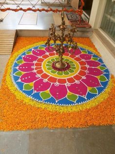 a colorful flower design is on the ground in front of a door with candles and decorations