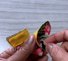 two hands are holding small pieces of fabric with yellow and pink flowers on them, next to each other