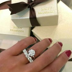 a woman's hand with two engagement rings on it and a gift box in the background