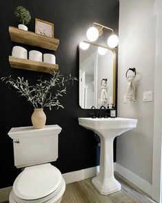 a white toilet sitting next to a sink in a bathroom under a mirror and lights