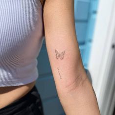 a woman's arm with a small butterfly tattoo on the left side of her arm