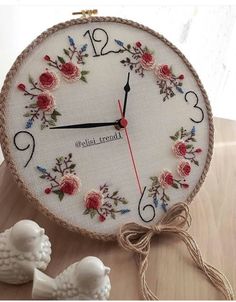 a white clock with red roses on it next to two figurines and a string