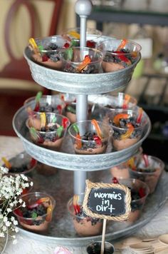 an assortment of desserts are displayed on a three tiered tray with a chalkboard sign