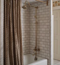 a bathroom with a tub, shower head and curtain