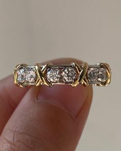 a close up of a person's hand holding a ring with three diamonds on it