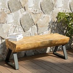 a wooden bench sitting on top of a hard wood floor next to a stone wall