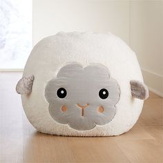 a white sheep pillow sitting on top of a wooden floor