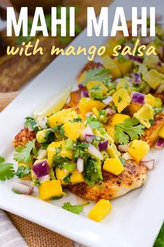 a white plate topped with chicken covered in mango salsa and garnished with cilantro