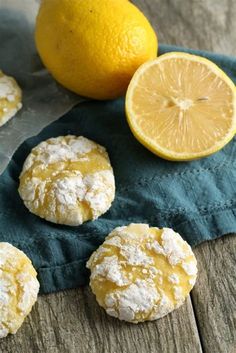 lemon cookies with powdered sugar are sitting on a blue towel next to an orange