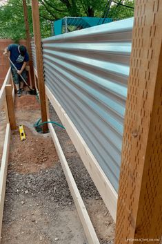 two men are working on the side of a building with metal siding and wood slats