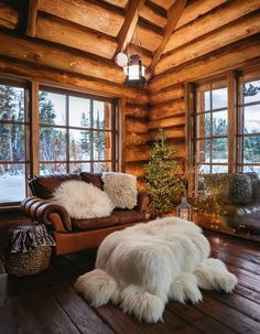 a living room filled with furniture and a christmas tree in front of two large windows