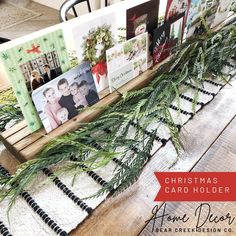 christmas card holder with pine branches and cards on it, sitting on a wooden table