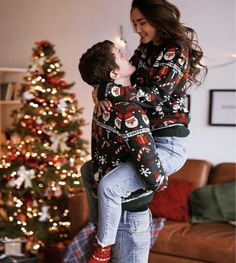 a boy and girl hugging in front of a christmas tree