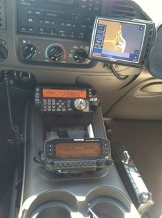 two radio's sitting in the center console of a vehicle with other electronics on it