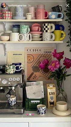 a coffee maker sitting on top of a counter next to some cups and saucers