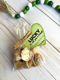 a candy bag filled with lucky charms on top of a white wooden table next to a green and white beaded necklace