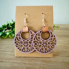 a pair of earrings sitting on top of a wooden table next to a plant pot