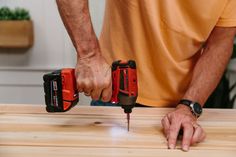 a man is working on a wooden table with two drillers and one screwdriver