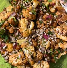 a green plate topped with cauliflower and broccoli covered in lots of seasoning