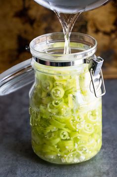 a jar filled with pickled green onions being poured into the jar by a spoon