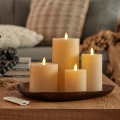 five lit candles sit on a tray in front of a couch