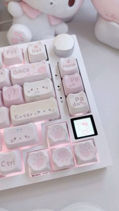 a white keyboard with pink keys sitting next to a teddy bear