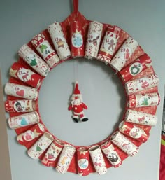 a christmas wreath made out of rolled up wrapping paper with a santa clause decoration hanging from it