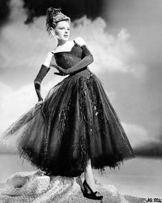 an old fashion photo of a woman in a black dress with feathers on her skirt