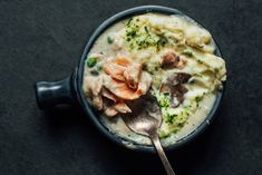 a bowl filled with mashed potatoes, meat and veggies next to a spoon