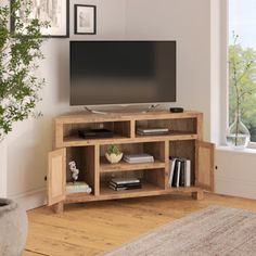 a living room with a large tv on top of a wooden entertainment center next to a window