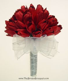 a bouquet of red tulips with white ribbon tied around the top and bottom