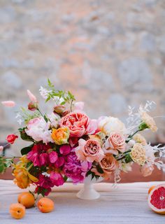 a vase filled with lots of flowers next to sliced oranges and grapefruit