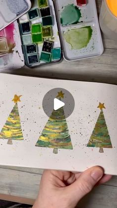 someone is painting christmas trees with watercolors