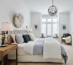 a bedroom with white walls and carpeted flooring has a large bed in front of a window