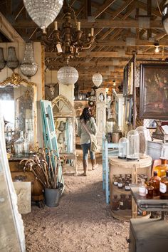 a woman walking through a store filled with furniture