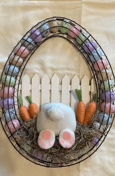 a bunny rabbit stuffed animal in a wire wreath with carrots and baby bunnies