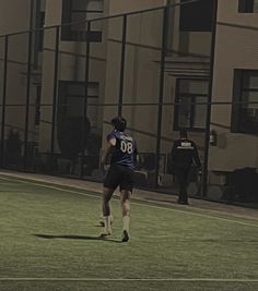 two men are playing soccer on the field in front of an apartment building at night