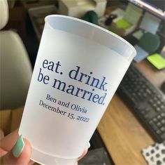 a person holding up a cup with the words eat drink be married written on it