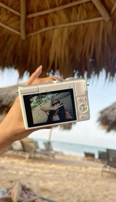 a person holding up a camera on the beach