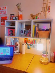 an open laptop computer sitting on top of a wooden desk next to a lamp and bookshelf