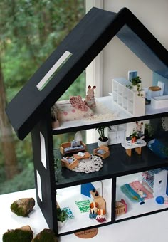 a doll house with furniture and decorations on the windowsill in front of a window