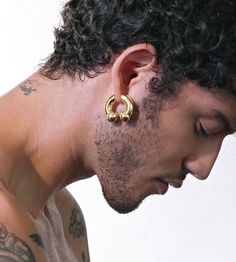 a man with tattoos and piercings on his ear is looking down at the ground