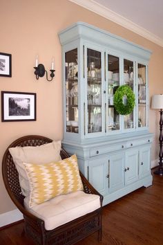 a blue china cabinet sitting in the corner of a living room