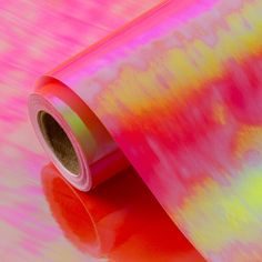 a roll of pink and yellow tie - dyed paper on top of a red surface