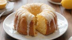 a lemon bunt cake on a white plate with a slice cut out and ready to be eaten