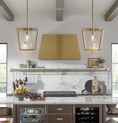 a kitchen with marble counter tops and gold pendant lights over the stove top, along with two wine coolers