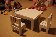 two dolls are sitting at a table with chairs and one doll is on the floor