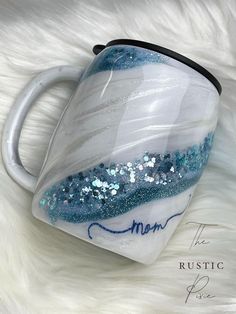 a white and blue coffee mug with some glitter on the inside is sitting on a furry surface